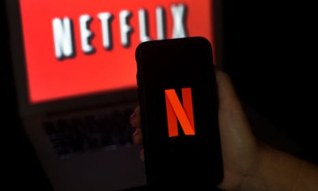 Photo illustration of a Netflix logo on a computer screen in the background and on a mobile phone in the foreground.