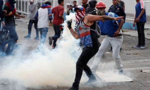 A demonstrator throws back a teargas canister during clashes with government security forces in Caracas on Tuesday.