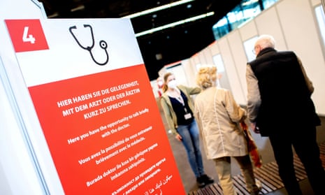Two people being shown to a booth in the background with a large red medical information sign in the foreground