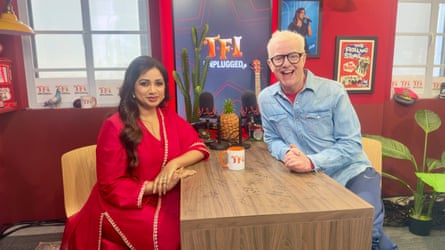 Shreya Ghoshal and Chris Evans sit either side of a wooden table on the TFI FRiday Unplugged set