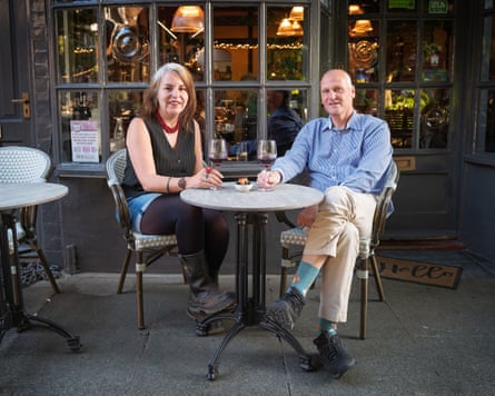 Becky and Andy sitting at a small table outside the front of a restaurant, smiling at the camera