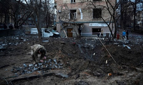 Un soldado ucraniano recoge fragmentos de misiles en un cráter dejado por un ataque ruso al lado de un edificio residencial en Kyiv.