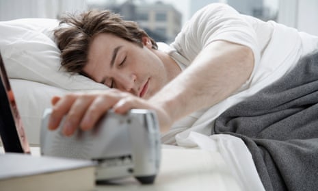 Young man switching alarm clock off
