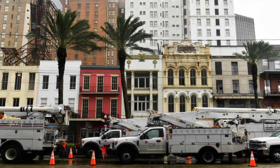 High winds blow palm trees as utility company bucket trucks are staged on Canal Street in New Orleans.