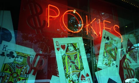 A neon pokies sign surrounded by giant playing cards in a window display