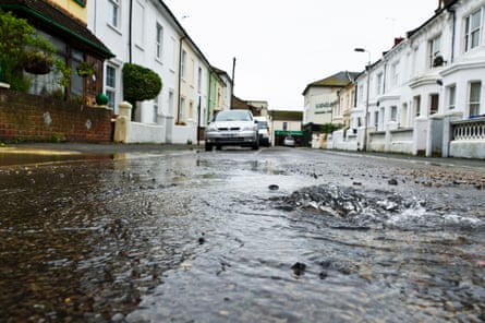 A water leak in the middle of a residential road caused by a burst water main.
