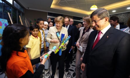 Turkey’s then-prime minister, Ahmet Davutoğlu (R), the German chancellor, Angela Merkel (L), and the EU council president, Donald Tusk (behind), meet children at a refugee camp in Turkey in April.