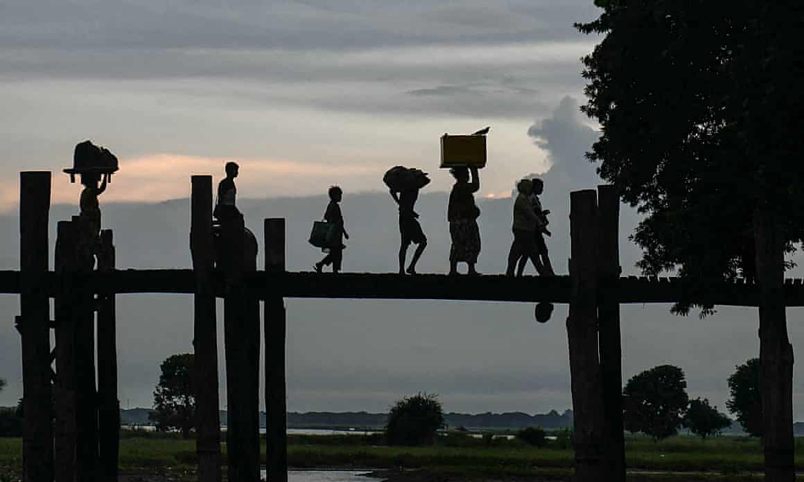 Silhouettes of people walking on a bridge