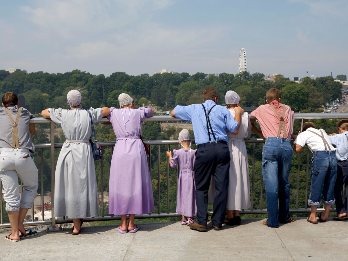 Mennonites leaning on a fence.