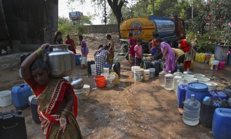 A woman walks with a vessel filled with water after collecting from a mobile water tanker at a slum area in Hyderabad, India.
