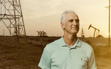 An elderly man in front of an oil field.