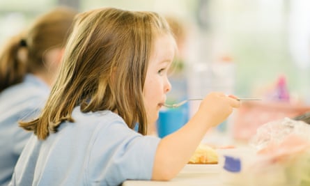 Young girl eating hot school dinner uk