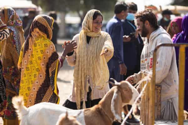 Two women and antheral speech with a goat successful the foreground