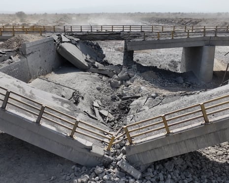 A damaged bridge lies in a riverbed, following US airstrikes in Iran.