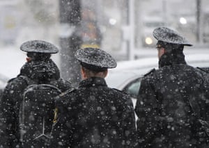 Soldiers in black coats and hats walking down a snowy street