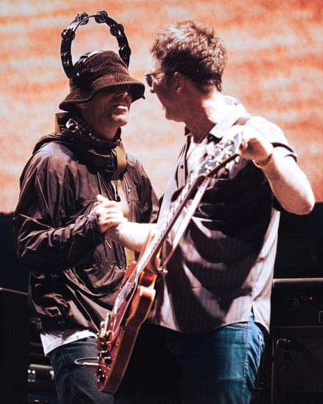 Liam and Noel Gallagher on stage, clasping hands, in Oasis: Don’t Look Back in Anger.