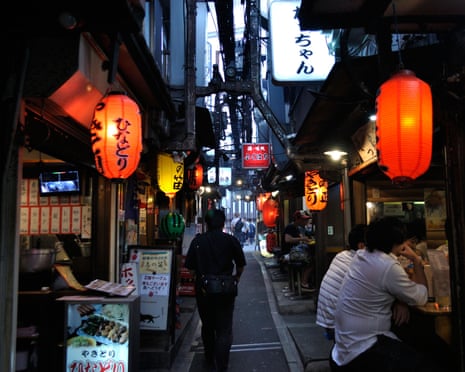 A lane with lanterns and people seated in Tokyo’s Shinjuku ward