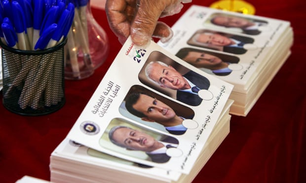A Syrian national living in Kuwait picks up a ballot bearing the images of the three Syrian presidential candidates. Photograph: Yasser Al-Zayyat/AFP/Getty Images