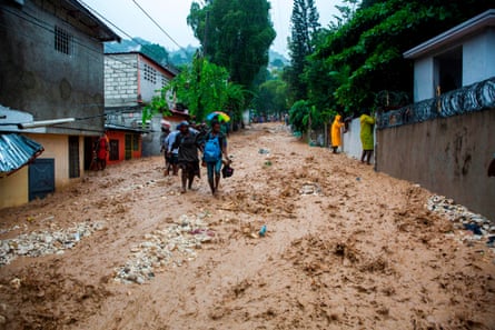 People walk across the flooded street in the neighborhood of Pétion ville, Haiti, on August 23, 2020 during the passage of Tropical Storm Laura.