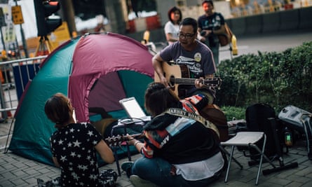 protesters in Hong Kong at Admiralty district sit next to a tent playing guitars and singing