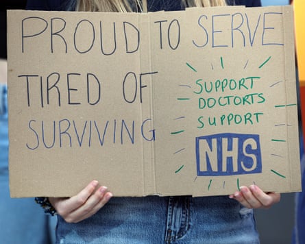 A striking resident doctor holds a placard during a picket outside the Royal Liverpool university hospital in Liverpool, 25 July 2025.