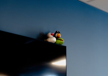 Two rubber ducks sit on top of a TV monitor against a blue wall.