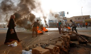 Protesters block a road with burning tyres and paving stones in Khartoum on Monday.