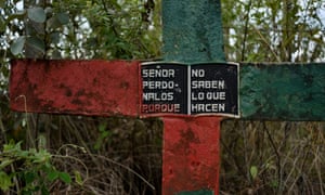 A cross on the side of the road painted in the colours of the Nasa indigenous people, reads, “Lord forgive them, fore they know not what they do.” Miranda, Cauca, Colombia