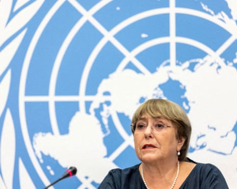 Michelle Bachelet speaking into a microphone with the blue and white UN logo in the background