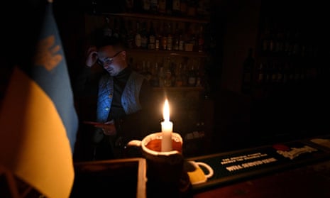 A bartender in Kyiv uses candlelight during a power cut.
