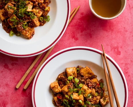 Fuschia Dunlop's juicy tofu in a spicy sauce on plates with chopsticks and a drink nearby