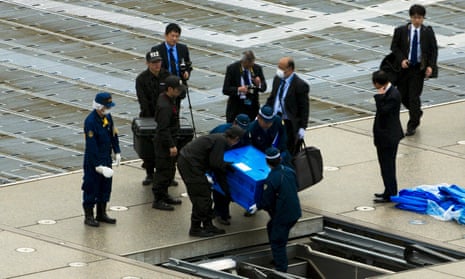 Officials carry a blue box that local media reported contains a drone from the rooftop of Shinzo Abe’s offices in Tokyo.