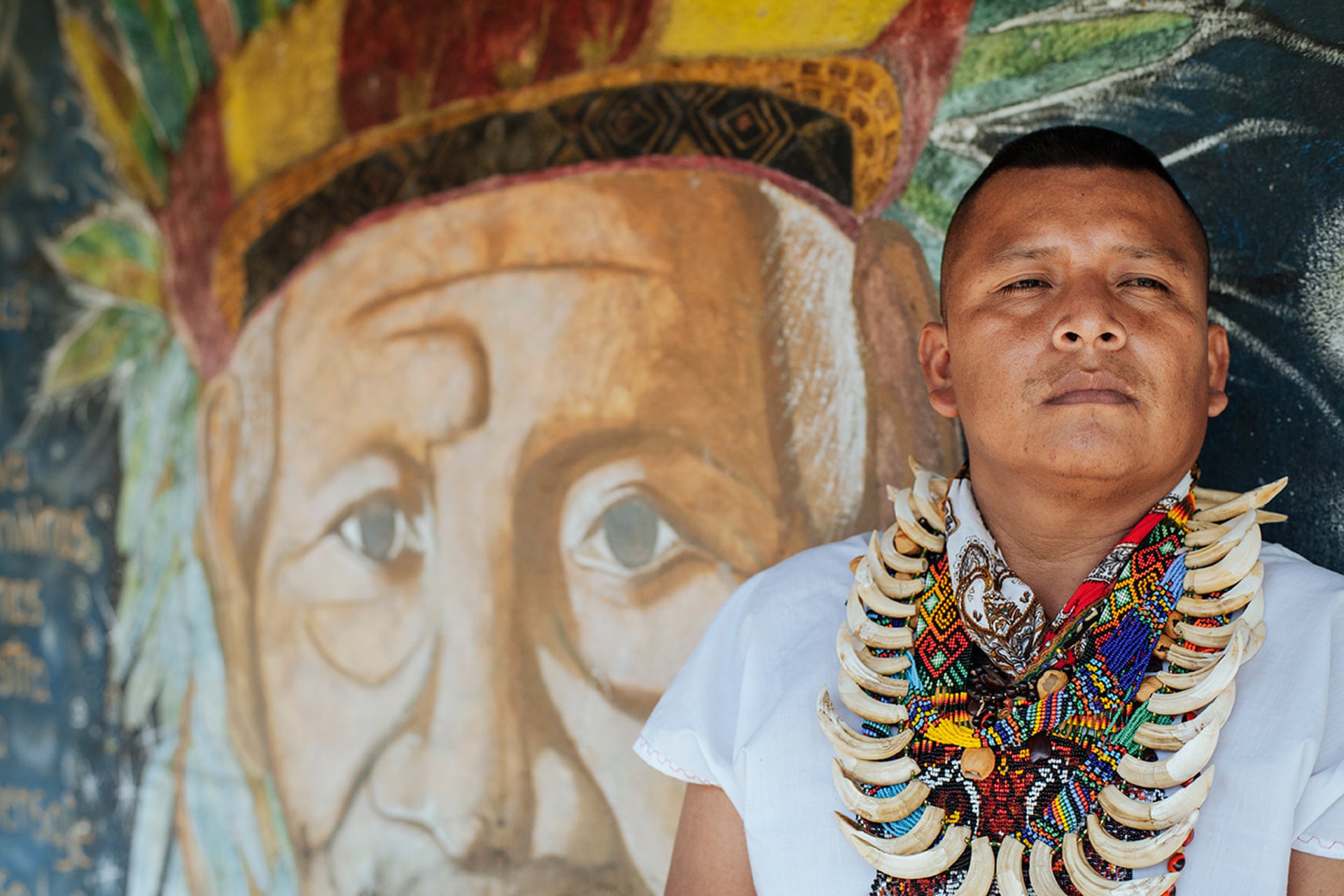 Sandro Piaguaje Cabrera stands alongside a mural of his grand-father, Buenavista’s founder and arguably most revered spiritual elder. Photograph: Mateo Barriga Salazar