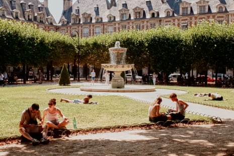 People relax on the grass at Place des Vosges during a heatwave in Paris, France.