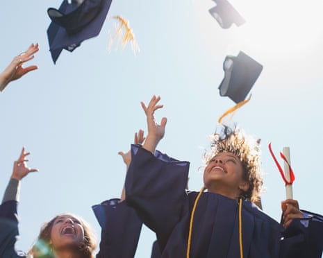 Black, female university graduates throw mortar-board hats in the air