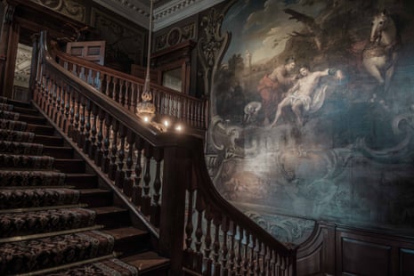Grand, ornate staircase with a painting covering one wall