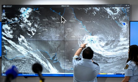 A person points at a large screen showing a satellite view of a cyclone