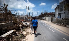 A girl and a woman walk past rubble on the island of Saint-Martin.