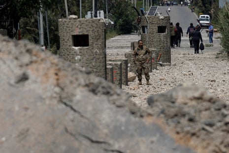 वर्दीधारी एक व्यक्ति लोगों को पुल से दूर जाते हुए देख रहा है।