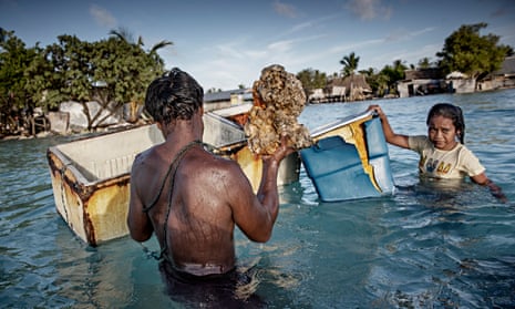 On the outskirts of Eita, Kiribati in the central Pacific, family members gather rocks and corals from the seabed to build a stone wall as protection against rising sea levels