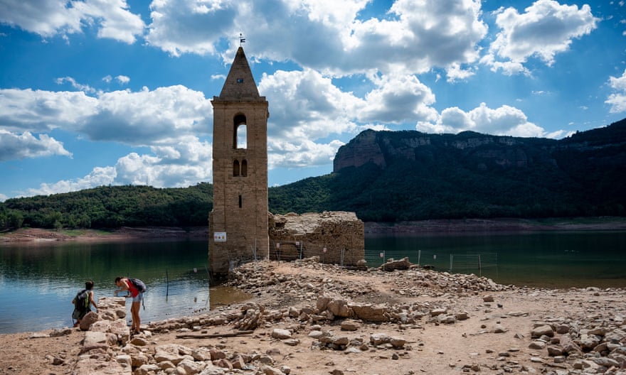 People stand in front of the ruins of the Basilica di Sant Roma de São.  Usually, the bell tower is the only part of the church visible above the water level.