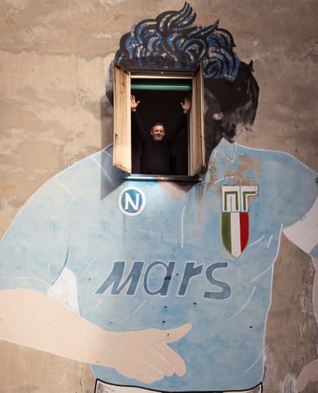 Ciro Maiello opens the window of his apartment in Naples, on which is painted the head of Diego Maradona.