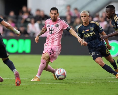 Lionel Messi in pink dribbles the ball while surrounded by three Philadelphia Union players in dark blue