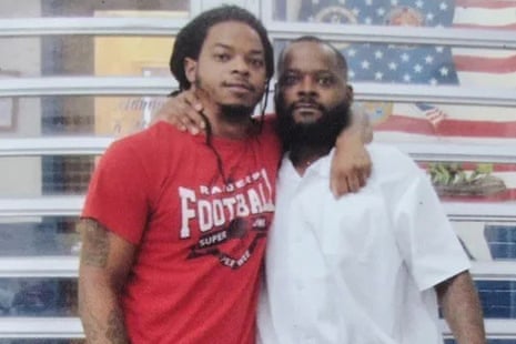 Toforest Johnson poses with an arm around his son's shoulders in front of a window