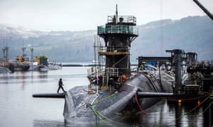 Submarine docked at base, hills behind