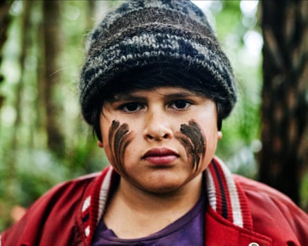 A boy in a forest with a beanie hat and stripes painted on his cheeks