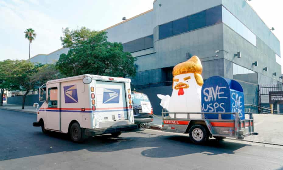 A postal worker passes by a “Save the Post Office” demonstration in Los Angeles, California.