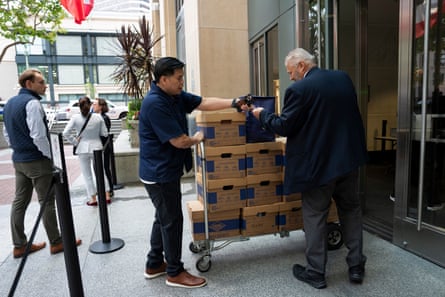 Man wheels large trolley stacked with boxes up to a doorway.