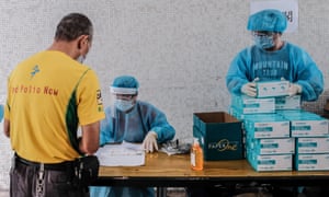 Medical workers wearing protective suits hand out test kits to local residents to collect samples for COVID-19 test at a residential block on August 7, 2020 in Hong Kong.