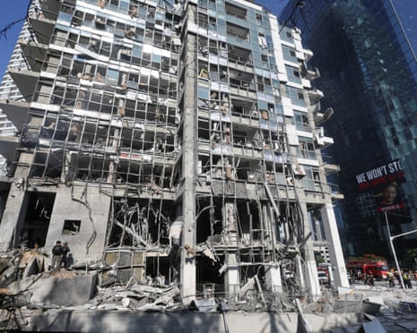 Emergency personnel stand near a damaged building following a strike from Iran on Israel, in Ramat Gan